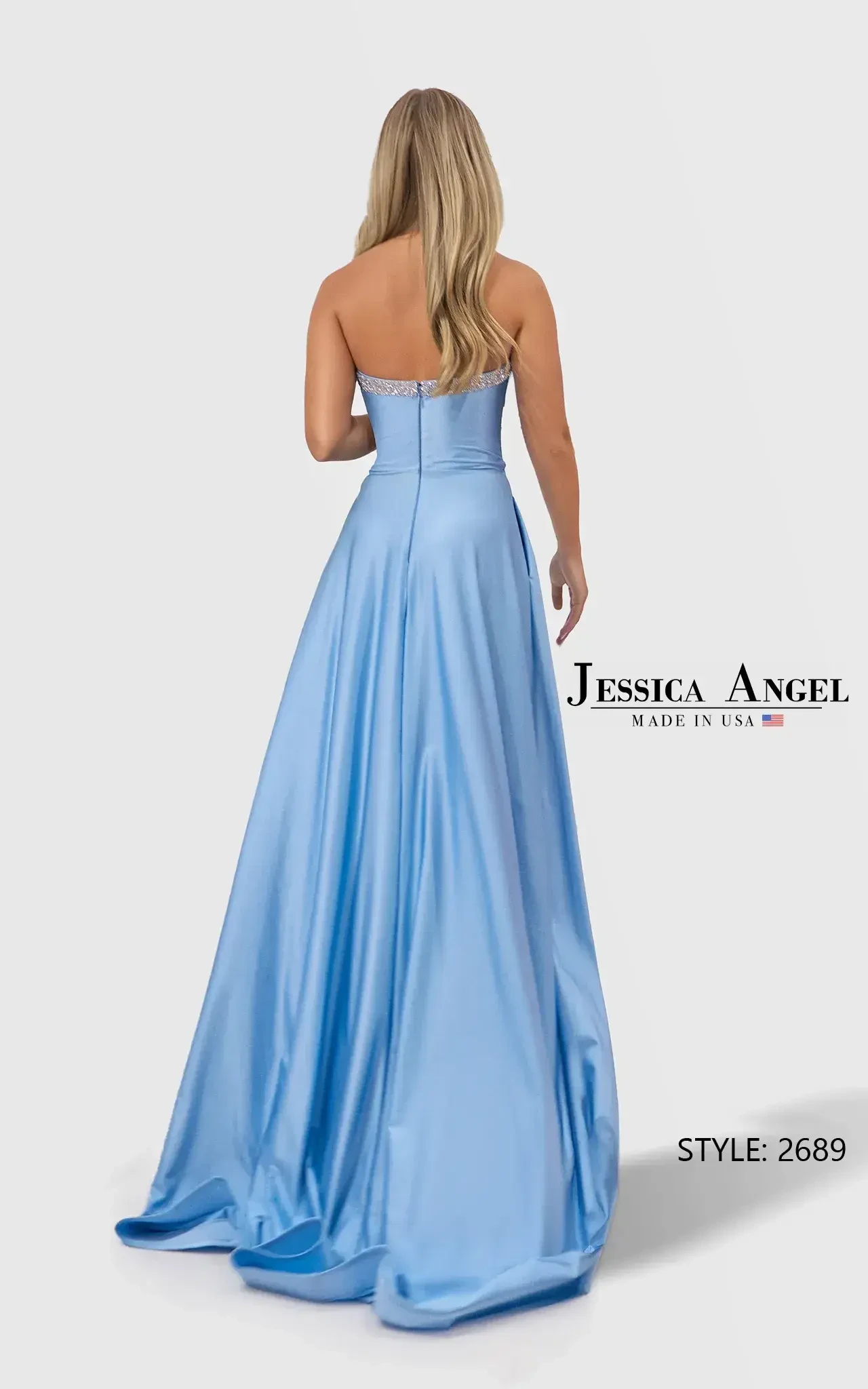 Woman in a strapless, light blue gown with cut-out details and a thigh-high slit, standing with a confident smile against a plain backdrop. Elegant and stylish.