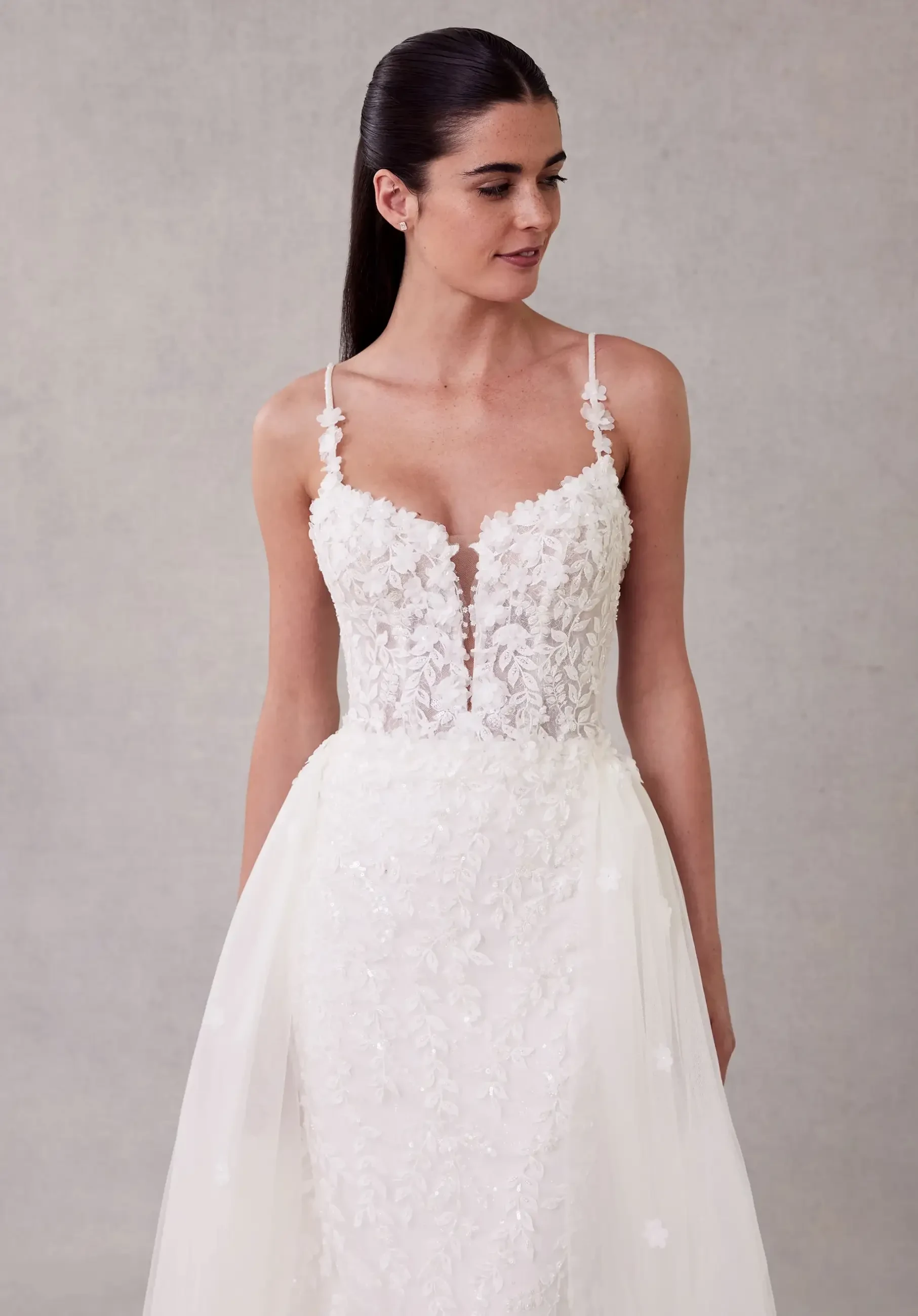 Model is wearing a fit-and-flare gown with three-dimensional beaded botanical lace, glitter net fabric for sparkle, and a detachable tulle overskirt.
