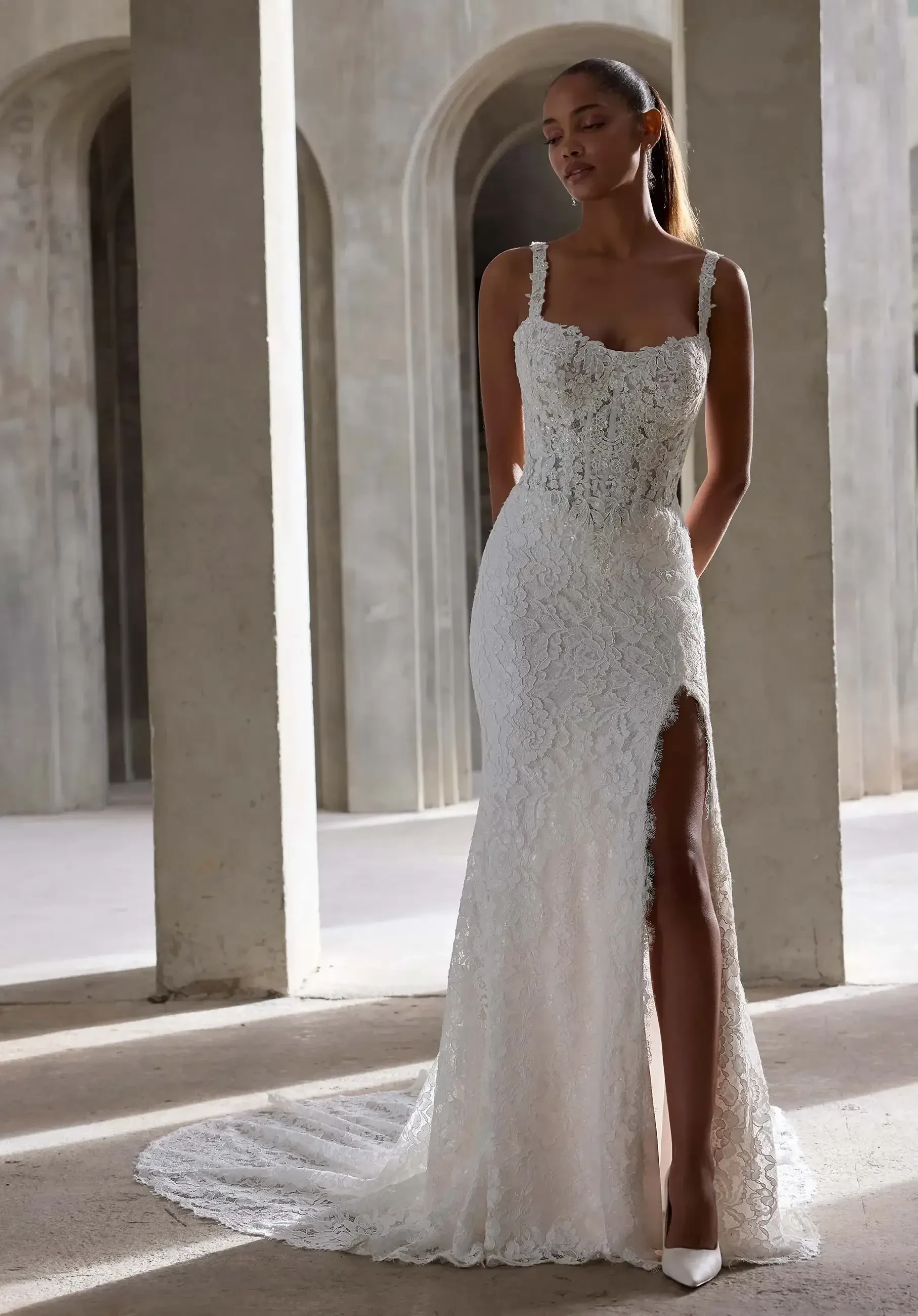 model is wearing a sleeveless lace sheath wedding gown